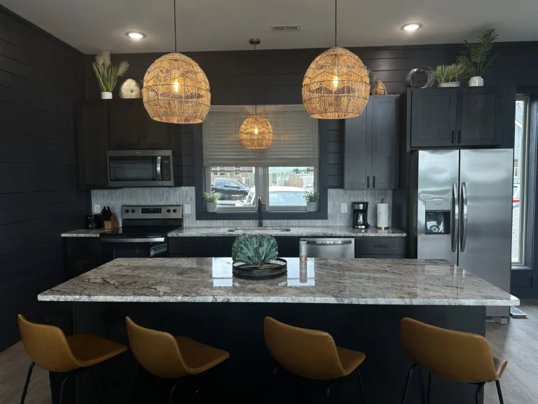 Luxury mountain cabin kitchen with a marble breakfast bar, high-end appliances, and modern-rustic interior design. A custom MCHB build in Sevierville, TN, featuring premium ceiling lighting and designer bar stools.