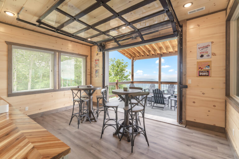 Rustic Traditional Cabin Bar interior featuring a modern, glass sliding garage-style door opening to an outdoor terrace. High-quality, functional design in the Smoky Mountains, TN.