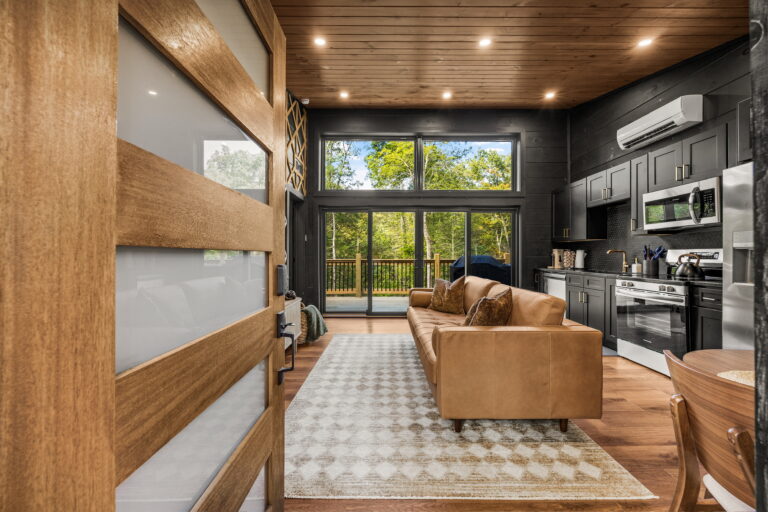 Luxury Modern Cabin Entrance, Sevierville TN. High-end interior design and open-concept living room with glass doors leading to the porch/deck.