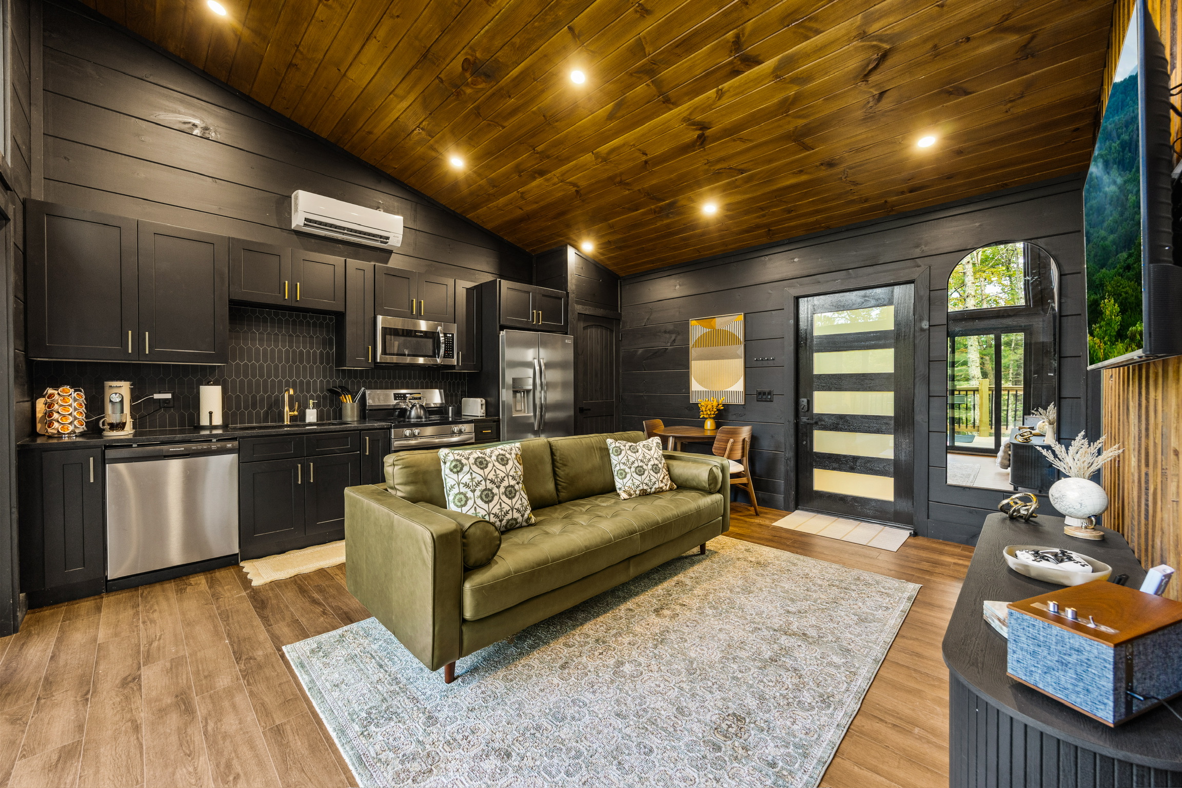 Beautiful Open Concept Living Room, Kitchen, and entrance space of a luxurious Contemporary Mountain Cabin Home. Featuring aesthetic details, high-end appliances, sophisticated interior design, custom-made finishes, and all-inclusive building services. Built by the best builders in Gatlinburg, Pigeon Forge, Sevierville, East Tennessee.