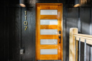 Trendy Minimalistic Cabin Entrance in East Tennessee. Crafted wooden door design with custom house numbering on a luxury mountain home.