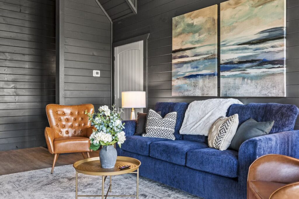 Contemporary Luxury Cabin Living Room featuring minimalist interior design. Color palette includes deep blues, grays, and rich brown leather accents. Smoky Mountains TN.