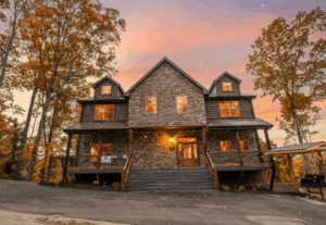 Front exterior of a beautiful luxury mountain cabin home, emanating warmth, fully lit and decorated, ready to welcome family for Thanksgiving gatherings in the Smoky Mountains.