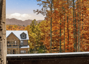 Beautiful Luxury Cabin exterior, graciously placed in the Smoky Mountains, East TN. Seen from a playful angle, the lush landscape shows autumn colors with light snow on the roof and ground.