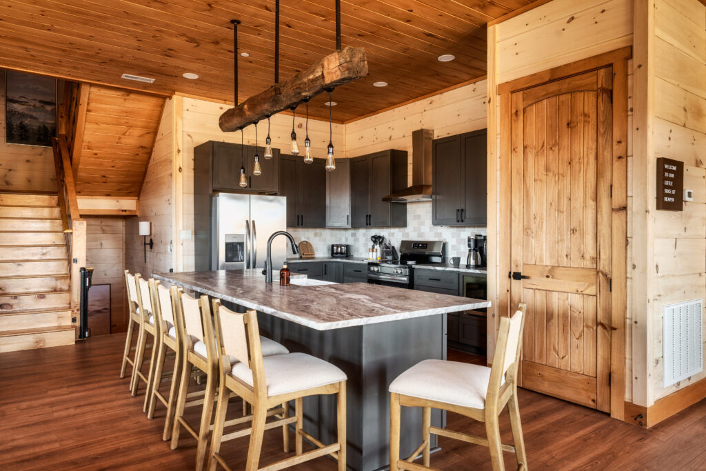 Perspective view of the custom-built luxury kitchen at Summit Skies. Showcasing marble quartz countertops, high-end professional appliances, and a seamless open-concept layout in a Smoky Mountain mountain home.