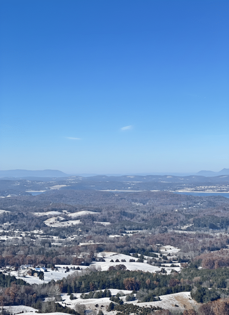 Winter valley landscape view from a luxury MCHB cabin in the Smoky Mountains. A panoramic vista of the Tennessee mountains under a blue sky with distant haze, showcasing premium site selection.