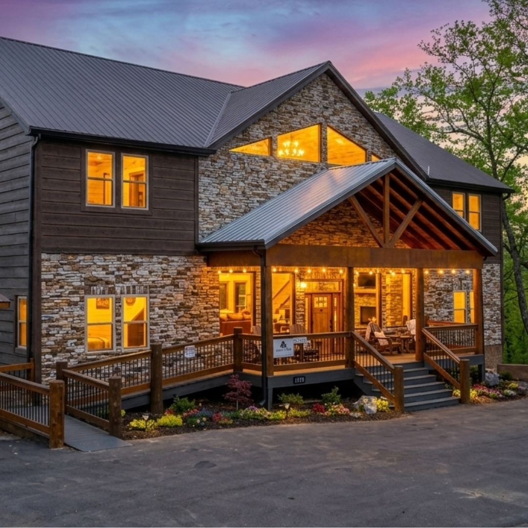 Sunset view of a luxury MCHB mountain home exterior in the Smoky Mountains. Features warm interior lighting, premium wood and stone finishes, and large windows reflecting the Tennessee sunset near Gatlinburg.