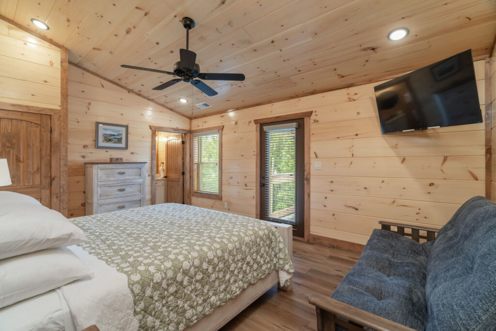 Spacious luxury bedroom interior at Shell Mountain Sunrise cabin. features a comfortable couch, flat-screen TV, and a private door leading to a scenic mountain terrace, built by MCHB.