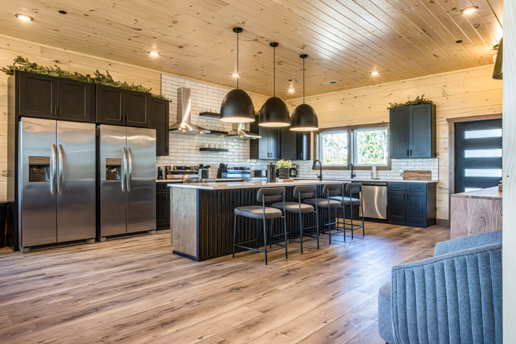 Side view of a high-capacity mountain kitchen with double refrigerators and modern designer lighting.