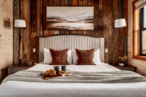 MCHB modern-classic luxury bedroom in Gatlinburg, TN. Features rich wooden walls, custom-made furniture, exquisite linens, and warm, integrated lighting in a Smoky Mountain cabin.