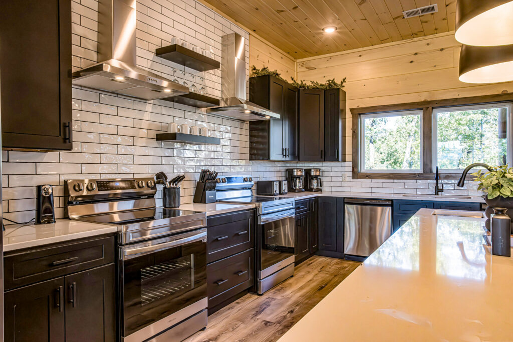 Deep perspective architectural view through an MCHB luxury kitchen in Sevierville, TN. Features lighting above the marble breakfast bar and a view to the formal dinner table at 3098 Smoky Bluff Trail.