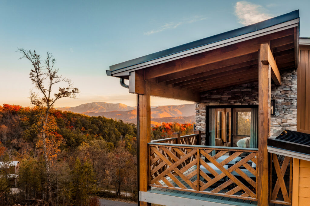 Side view of an intimate MCHB luxury balcony with comfortable outdoor seating and direct door access from a bedroom. Features a contemporary-traditional mountain design in Gatlinburg, TN.