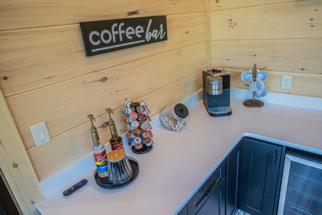 Overhead shot of an MCHB luxury coffee bar station in Sevierville, TN. Features a modern pod machine, artisan syrups, a custom "Coffee Bar" sign, and a high-end white marble countertop.