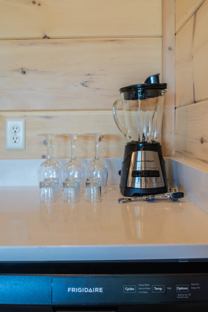 Detail of an MCHB luxury marble countertop in Sevierville, TN. Shows integrated dishwasher controls, designer glassware, and high-performance kitchen engineering.