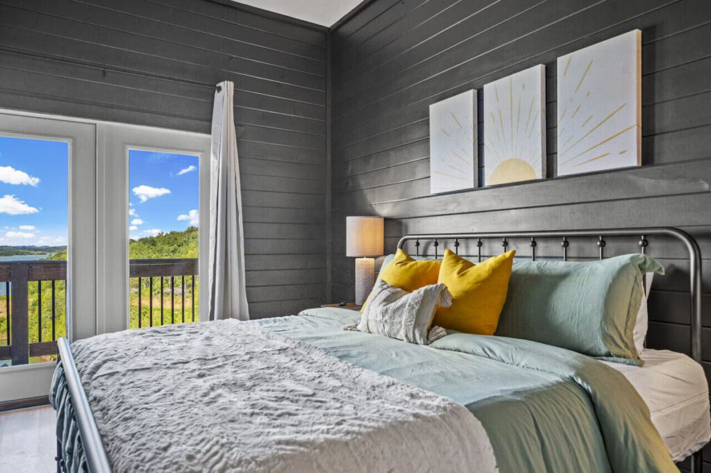 MCHB modern-contemporary luxury bedroom in Sevierville, TN. Features floor-to-ceiling windows, terrace access, and a panoramic view of the Smoky Mountain lake landscape.