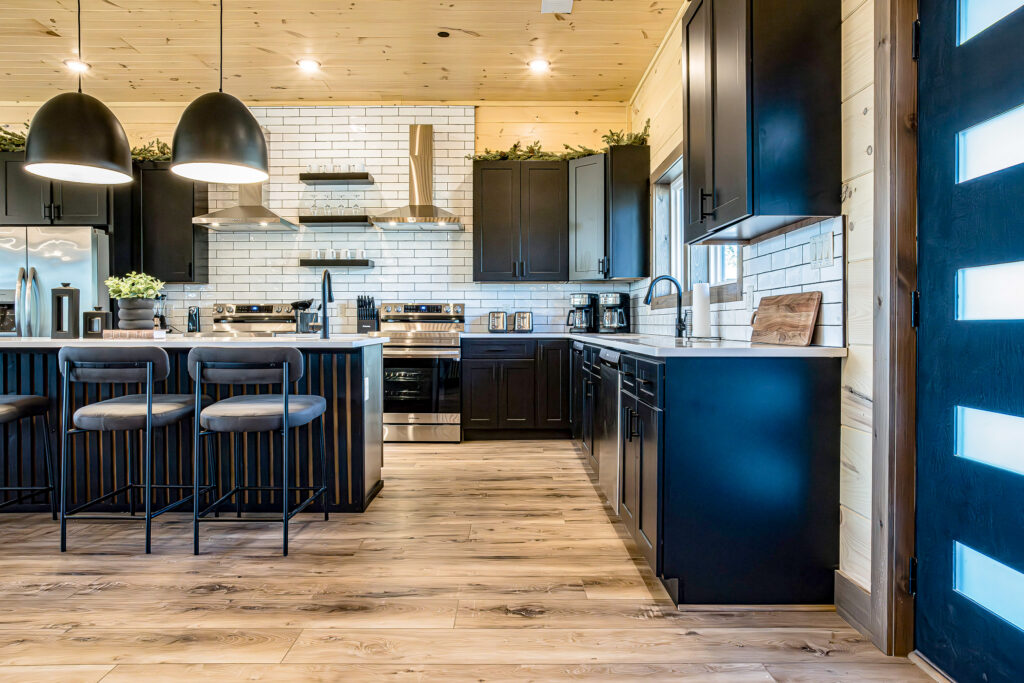 Side view of a custom MCHB kitchen island with white marble countertops, an integrated dishwasher, and a view of the seamless open-concept home layout in the Smoky Mountains.