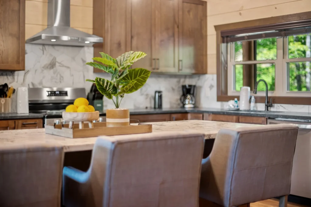 Close-up side view of an MCHB kitchen island with custom marble countertops, high-end comfortable bar chairs, custom cabinets, and durable hardwood flooring in a luxury mountain home.