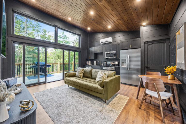 Side view of a mini cabin living area in Sevierville, featuring a space-saving dining table, high-end appliances, and large glass doors to the deck.