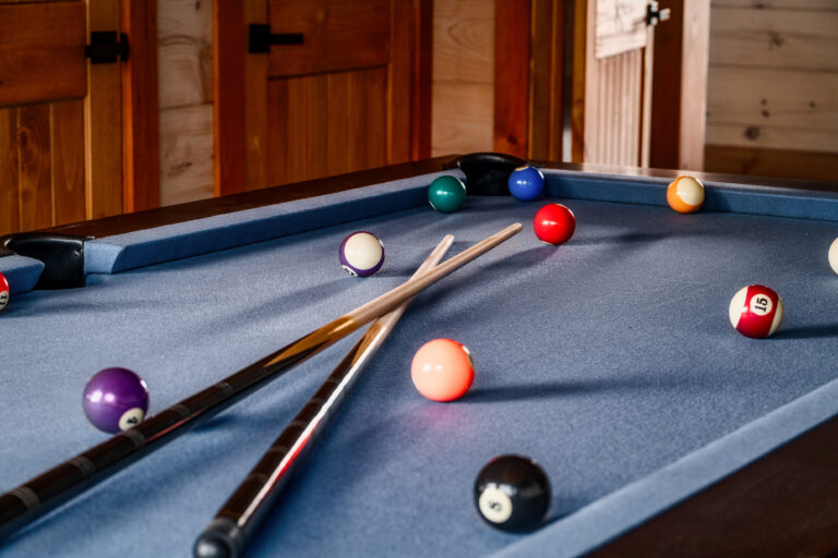 Professional-grade pool table in a spacious game room of a Pigeon Forge luxury cabin, featuring natural wood accents and mountain views.
