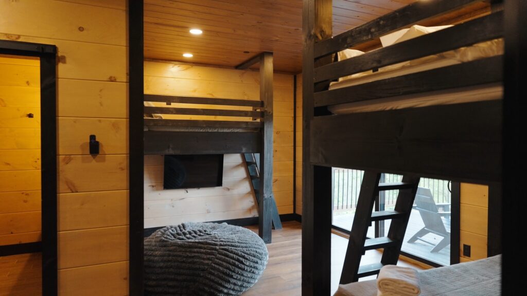 Custom bunk bed room at 3264 Laurel Cove Trail featuring built-in bunks, a cozy youth bean bag, a flat-screen TV, and sliding door access to the terrace deck.