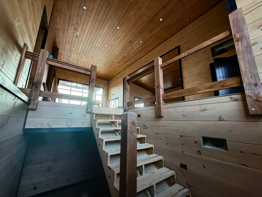 Interior construction framing shot by MCHB showing a grand staircase layout, load-bearing studs, and soaring vaulted ceilings under development.