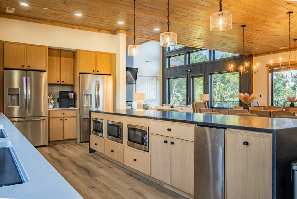 Ample and elegant luxury estate kitchen inside Reedmont Celeste Estate, featuring two massive sub-zero refrigerators, three integrated wall ovens, and custom luxury lighting over expansive countertops.
