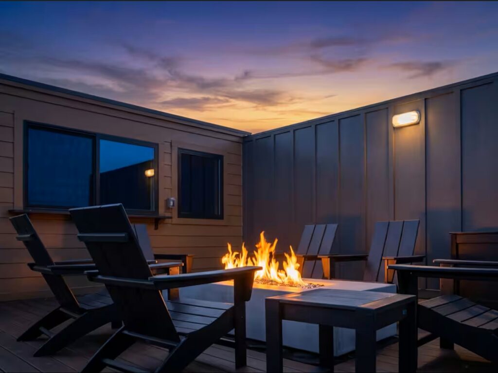 High-elevation rooftop event space deck featuring a modern stone gas fireplace, premium reclining lounge chairs, and an unobstructed panoramic view of the Smoky Mountain ridges during afternoon golden hour.
