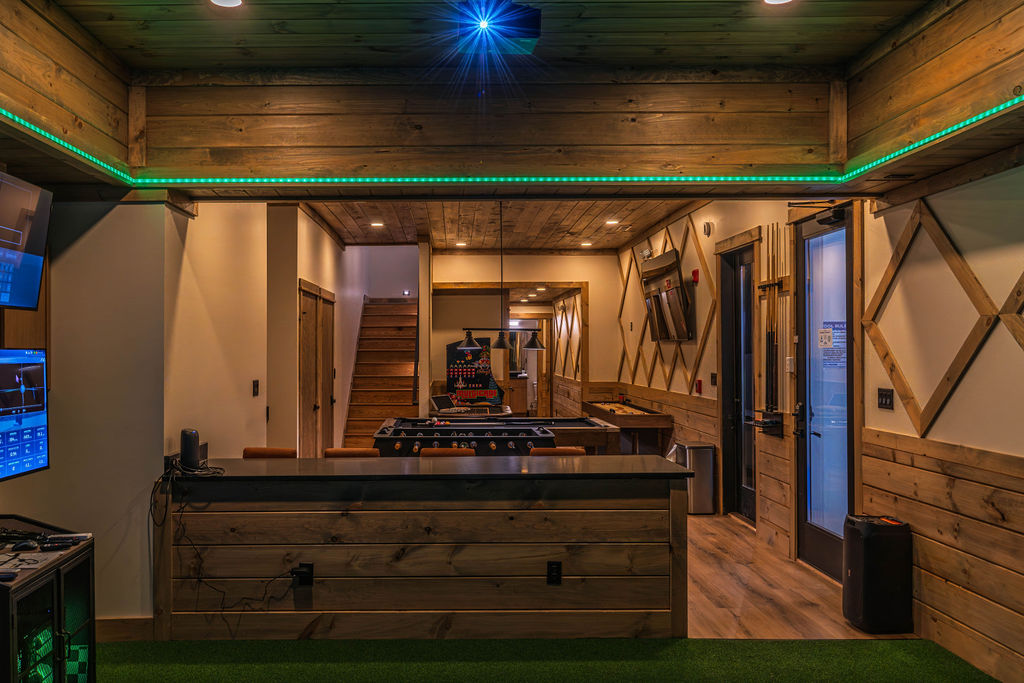 Interior view of a fully equipped luxury cabin game room featuring commercial arcade machines, gaming stations, and custom recreation amenities