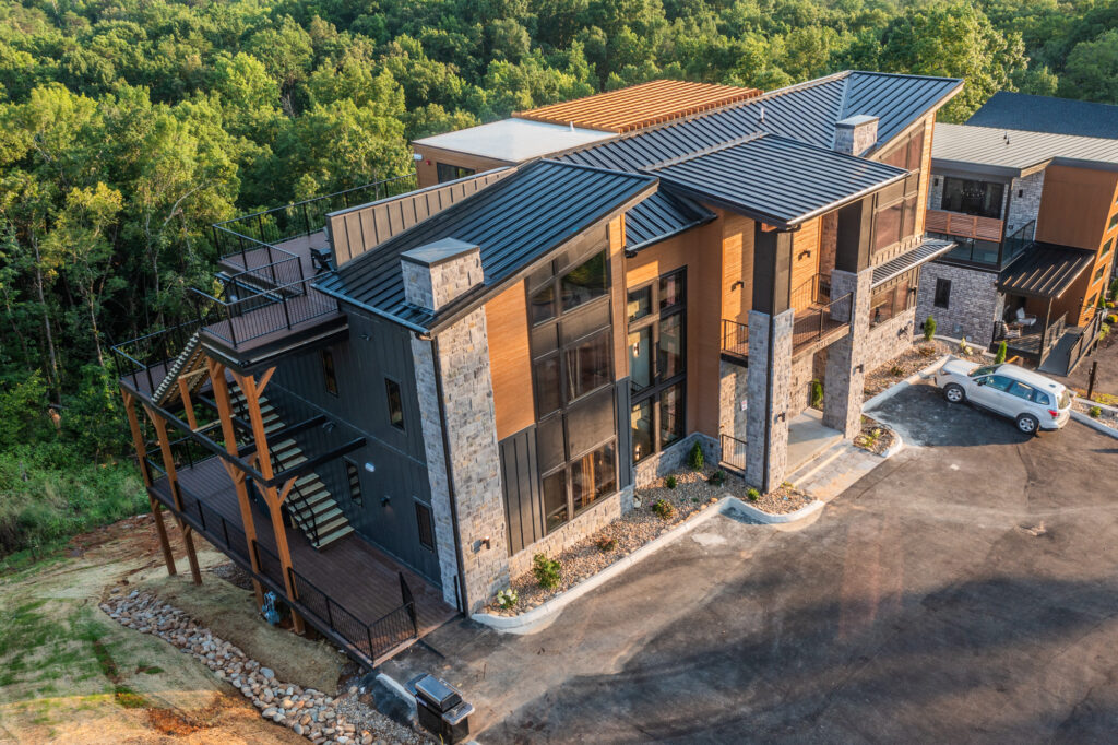 High-angle aerial tilt-down view of a luxury mountain home facade surrounded by dense green forest foliage in Sevierville Tennessee