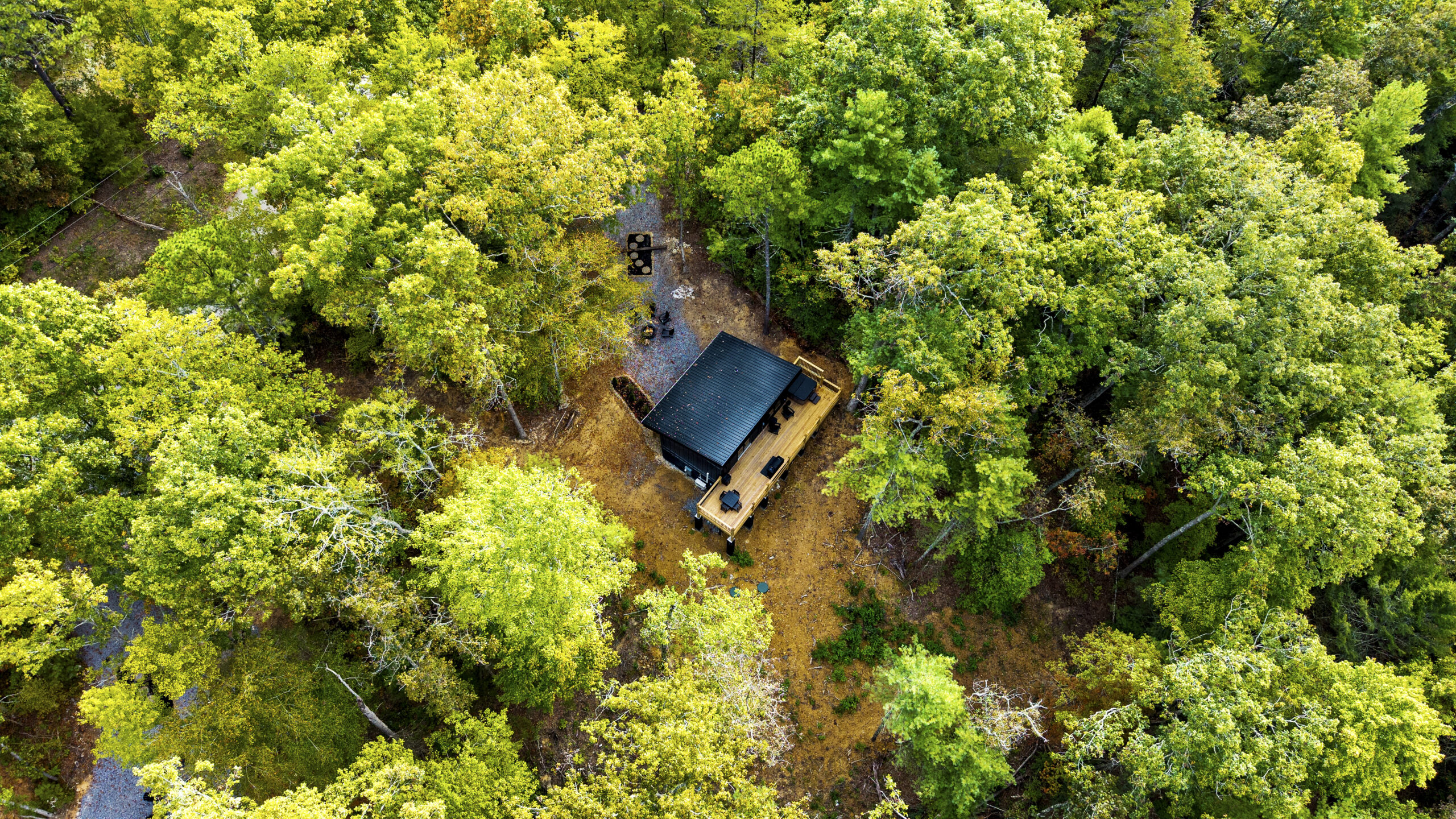 Overhead aerial drone view looking straight down at a custom mountain cabin nestled deep within a dense, green forest canopy in Gatlinburg TN