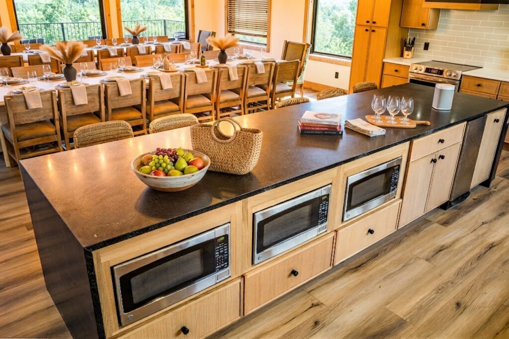 Marble kitchen island with three integrated built-in speed ovens below, looking into an expansive dining room that seats over 12 guests in Pigeon Forge